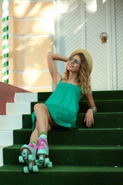 Happy girl with retro roller skates sitting on stairs