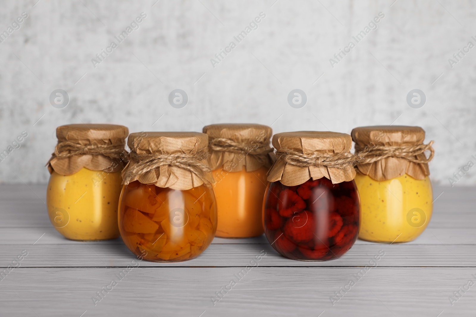 Photo of Jars with canned fruit jams on wooden table