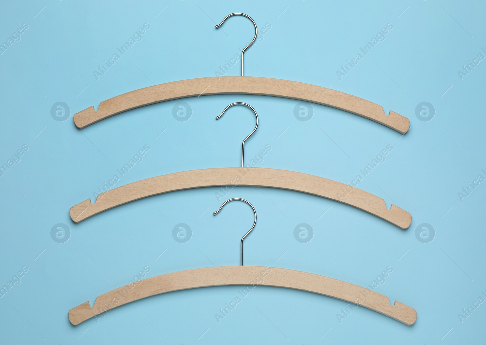 Photo of Empty hangers on light blue background, flat lay