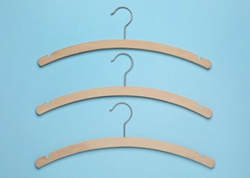 Empty hangers on light blue background, flat lay