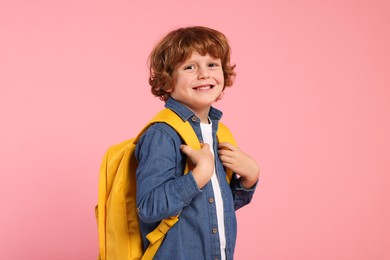 Photo of Happy schoolboy with backpack on pink background