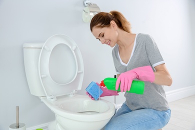 Photo of Woman cleaning toilet bowl in bathroom