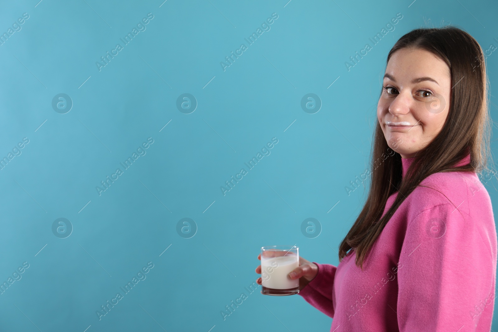 Photo of Happy woman with milk mustache holding glass of drink on light blue background. Space for text