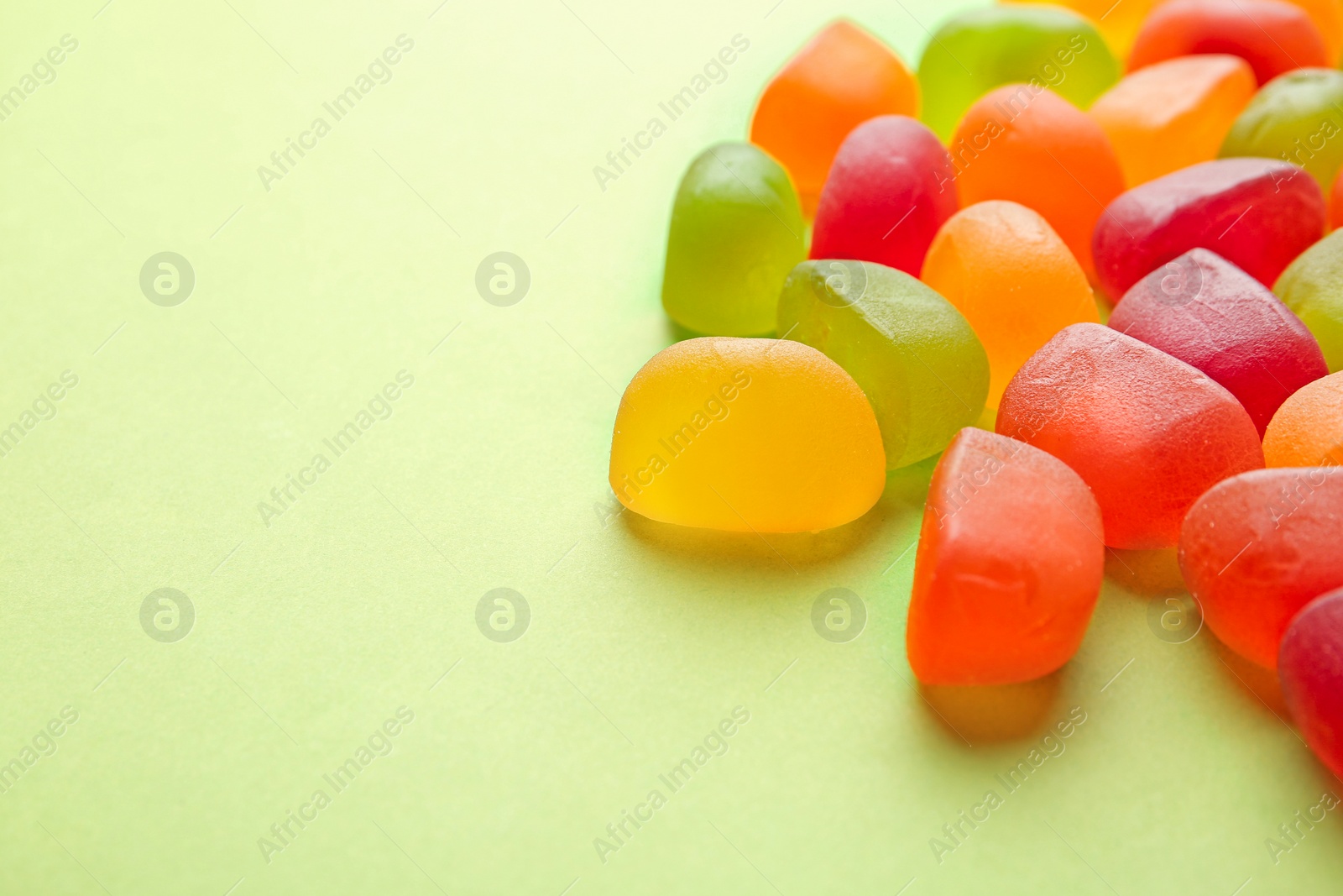 Photo of Sweet jelly candies on green background. Space for text