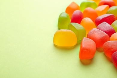 Photo of Sweet jelly candies on green background. Space for text