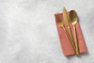 Stylish cutlery and napkin on light grey table, top view. Space for text