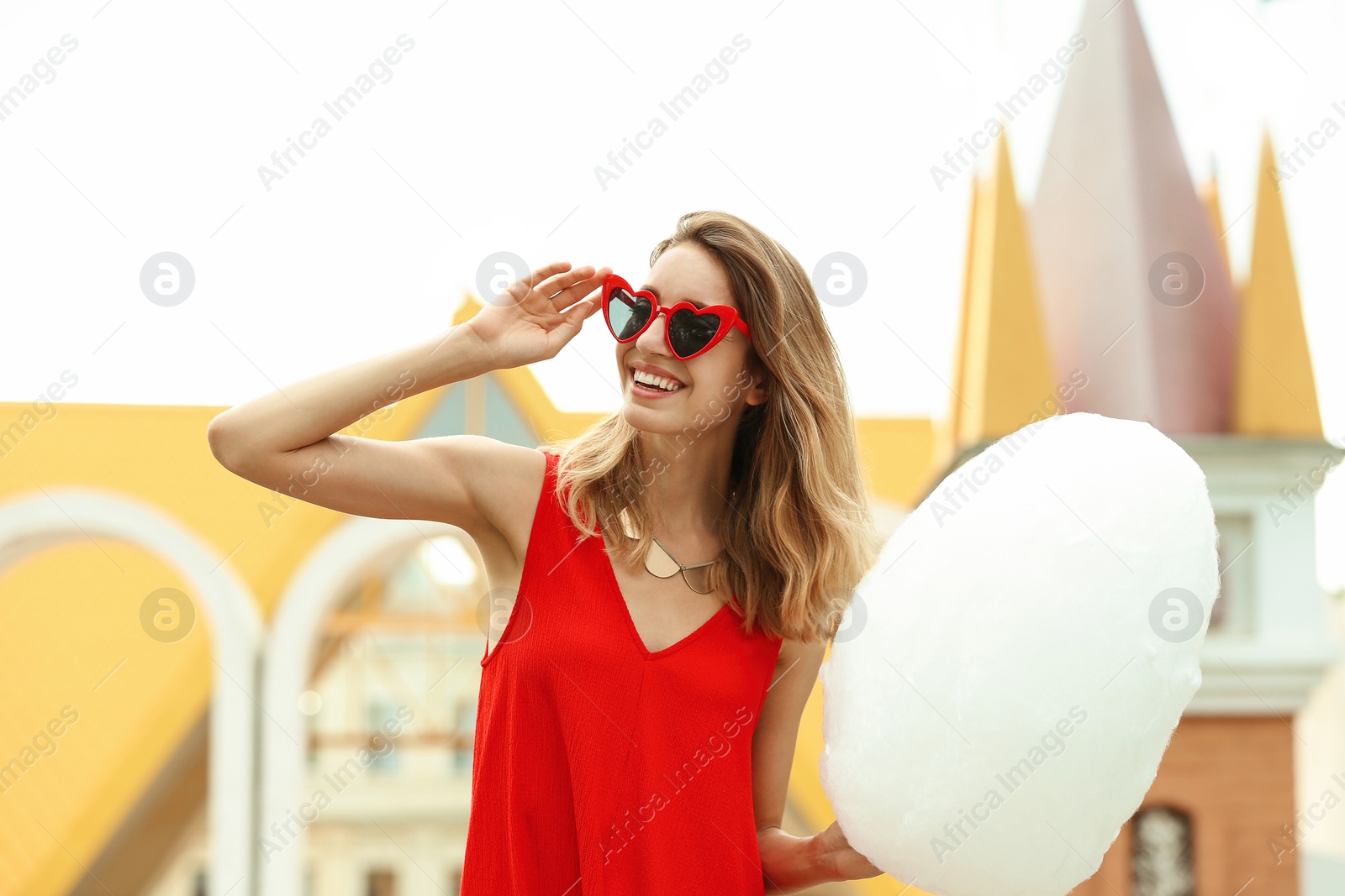 Photo of Happy young woman with cotton candy in amusement park