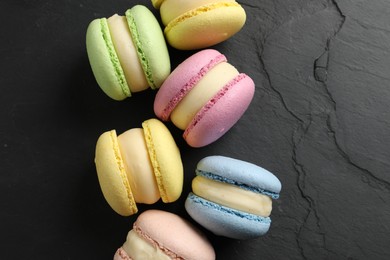 Photo of Delicious colorful macarons on black table, flat lay