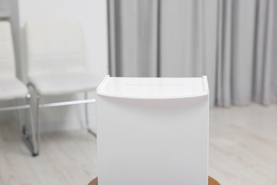 Photo of White ballot box on blurred background, closeup