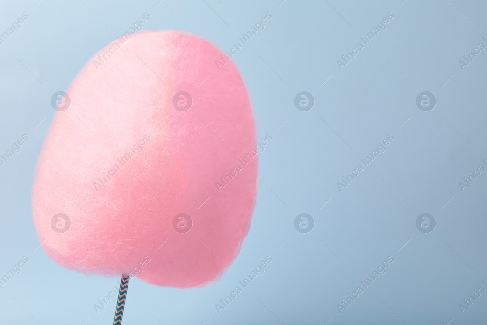 Photo of One sweet pink cotton candy on light blue background, space for text