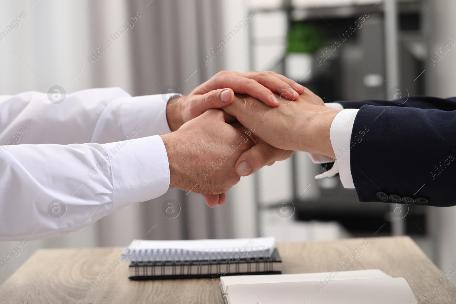 Photo of Trust and deal. Men joining hands in office, closeup