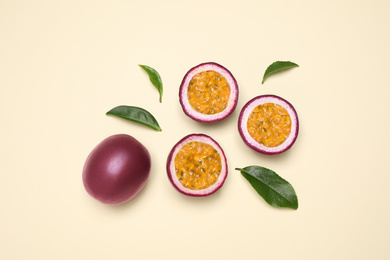 Photo of Fresh ripe passion fruits (maracuyas) with leaves on beige background, flat lay