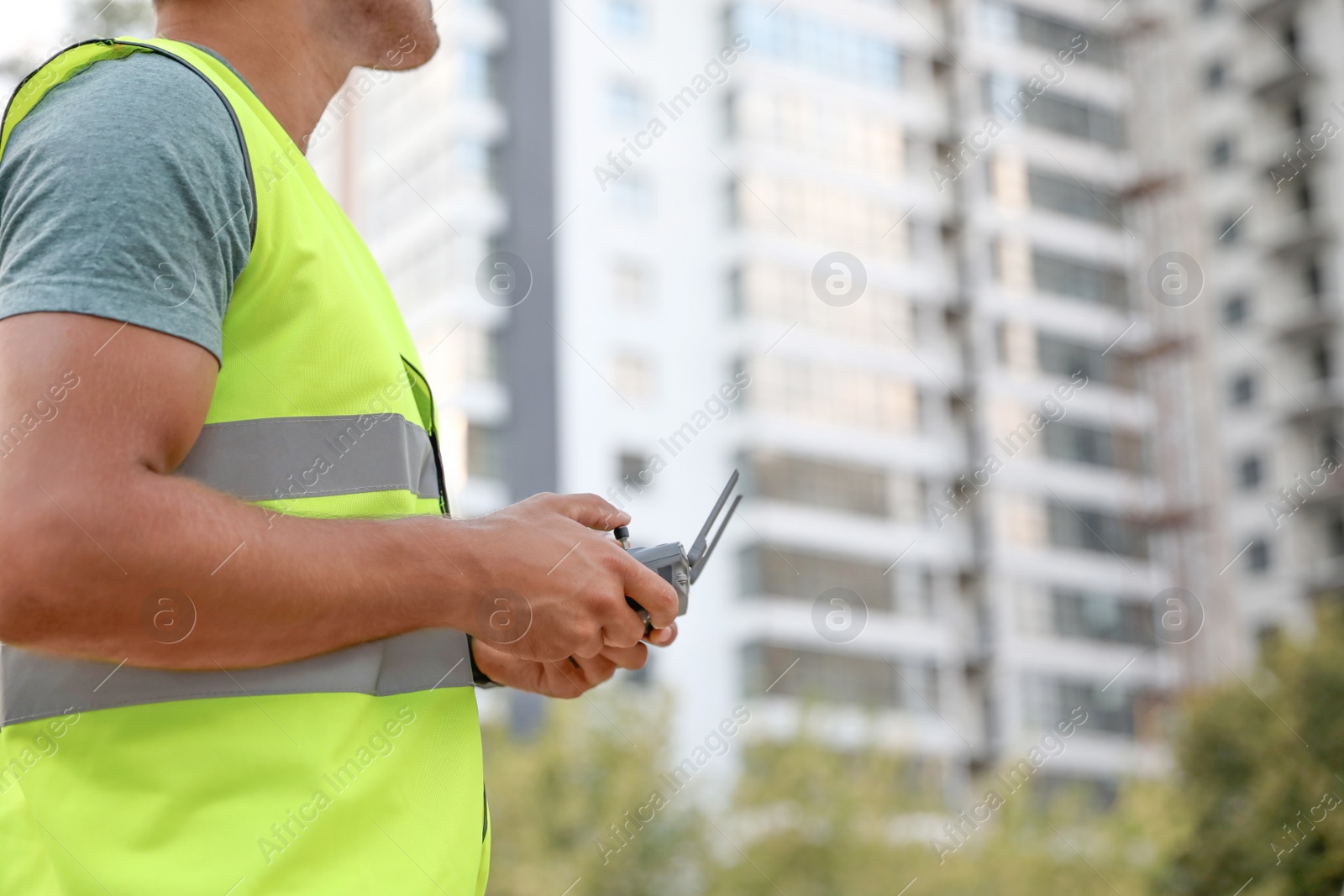 Photo of Builder operating drone with remote control at construction site, closeup. Aerial photography