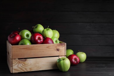 Photo of Fresh ripe red and green apples on black wooden table, space for text
