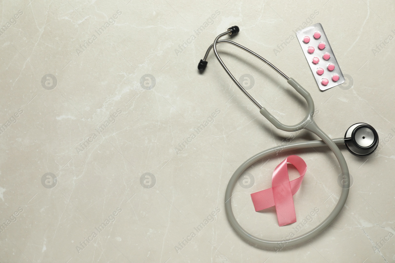 Photo of Breast cancer awareness. Pink ribbon, stethoscope and pills on light grey table, flat lay. Space for text