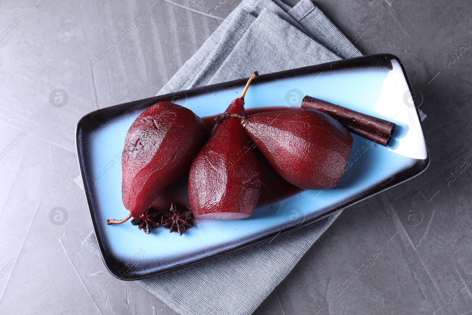 Photo of Tasty red wine poached pears and spices on grey table, top view