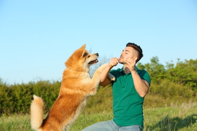 Young man playing with adorable Akita Inu dog in park