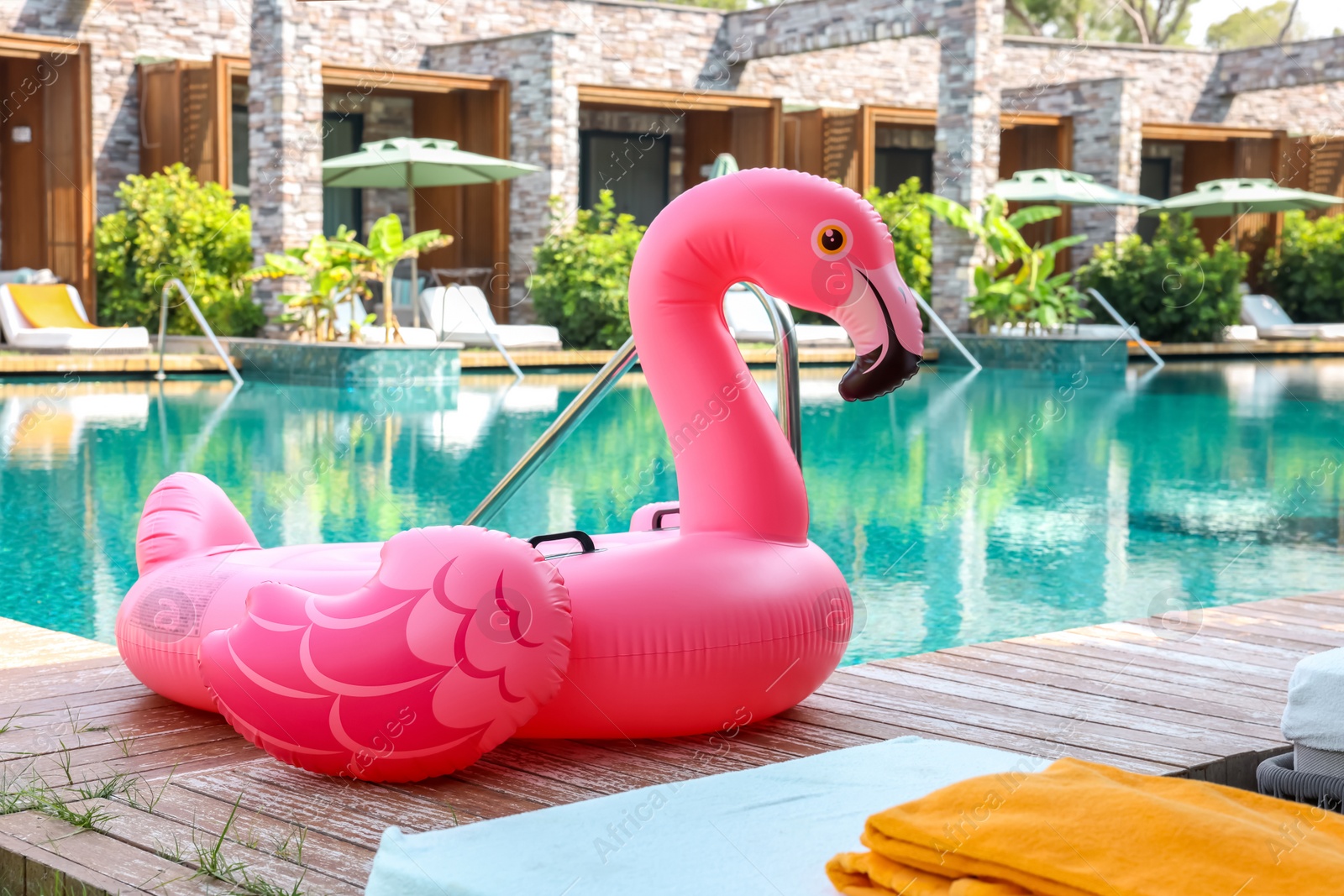 Photo of Float in shape of flamingo on wooden deck near swimming pool at luxury resort