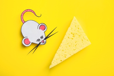 Photo of Paper mouse with piece of cheese on yellow background, flat lay