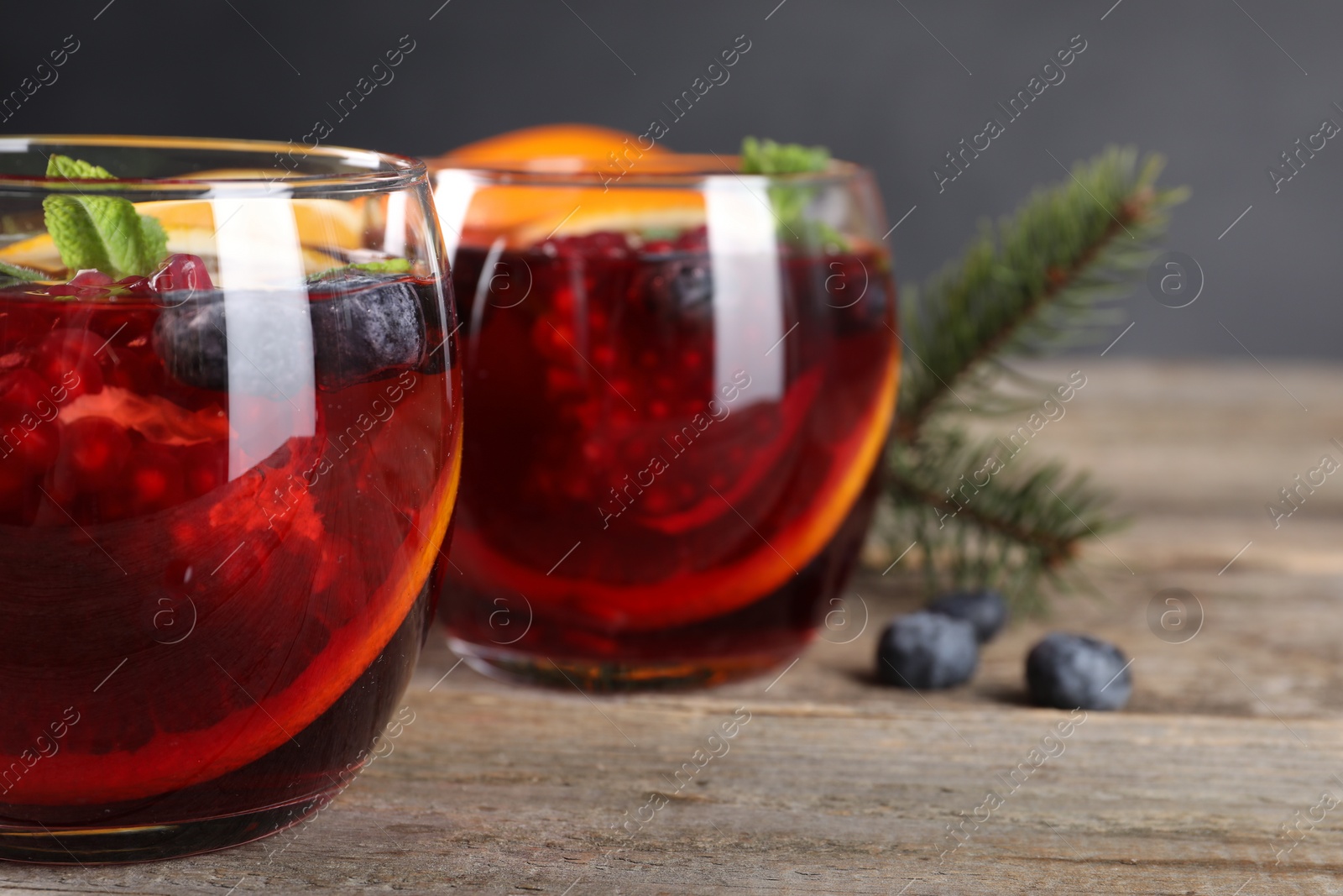 Photo of Aromatic Christmas Sangria drink in glasses on wooden table, closeup