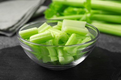 Photo of Bowl with fresh green cut celery on grey table, closeup