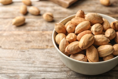Photo of Pecan nuts in bowl on wooden table, space for text
