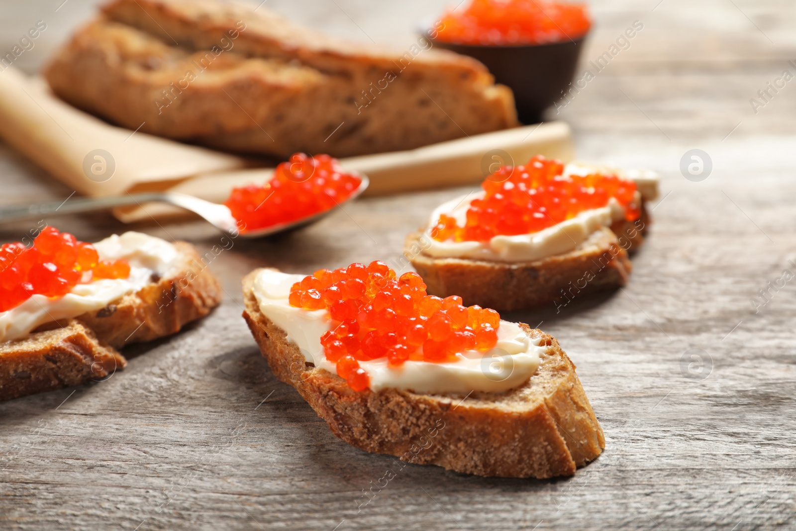 Photo of Sandwiches with red caviar on wooden table