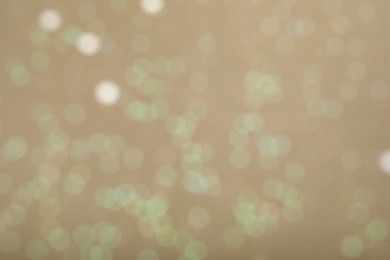 Photo of Blurred view of glitter on beige background. Bokeh effect