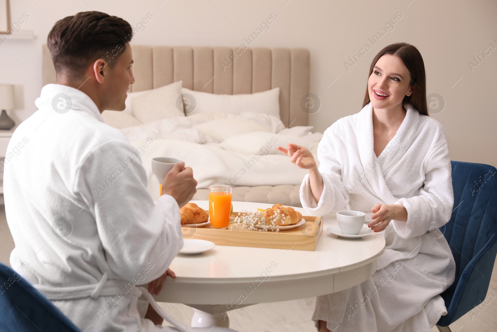 Photo of Happy couple in bathrobes having breakfast at home