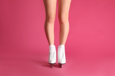 Photo of Woman in elegant white ice skates on pink background, closeup of legs