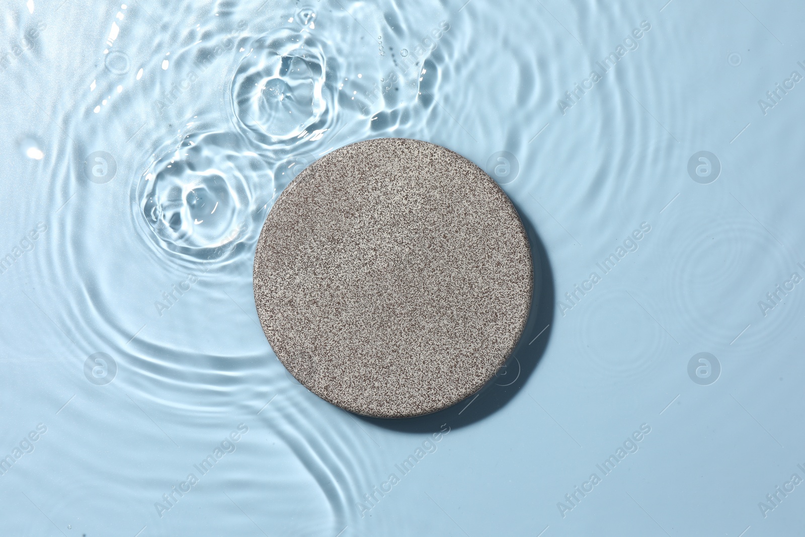 Photo of Presentation for product. Stone podium in water on light blue background, top view