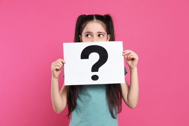 Photo of Girl holding sheet of paper with question mark on pink background