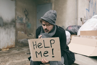 Photo of Poor young man with HELP ME sign at dump