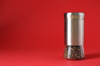 Photo of Pepper shaker on red background, space for text