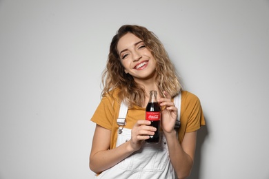 MYKOLAIV, UKRAINE - NOVEMBER 28, 2018: Young woman with bottle of Coca-Cola on white background