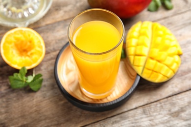 Glass of fresh mango drink and tropical fruits on wooden table