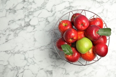 Photo of Green apple among red ones in metal basket and space for text on table, top view. Be different