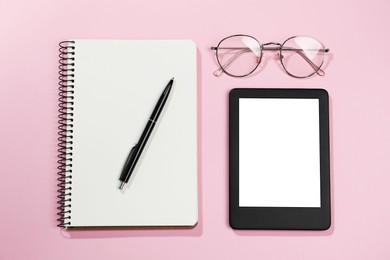 Photo of E-book reader, notebook and glasses on pink background, flat lay. Space for text