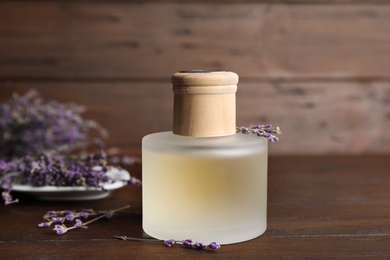 Photo of Bottle with aromatic lavender oil on wooden table