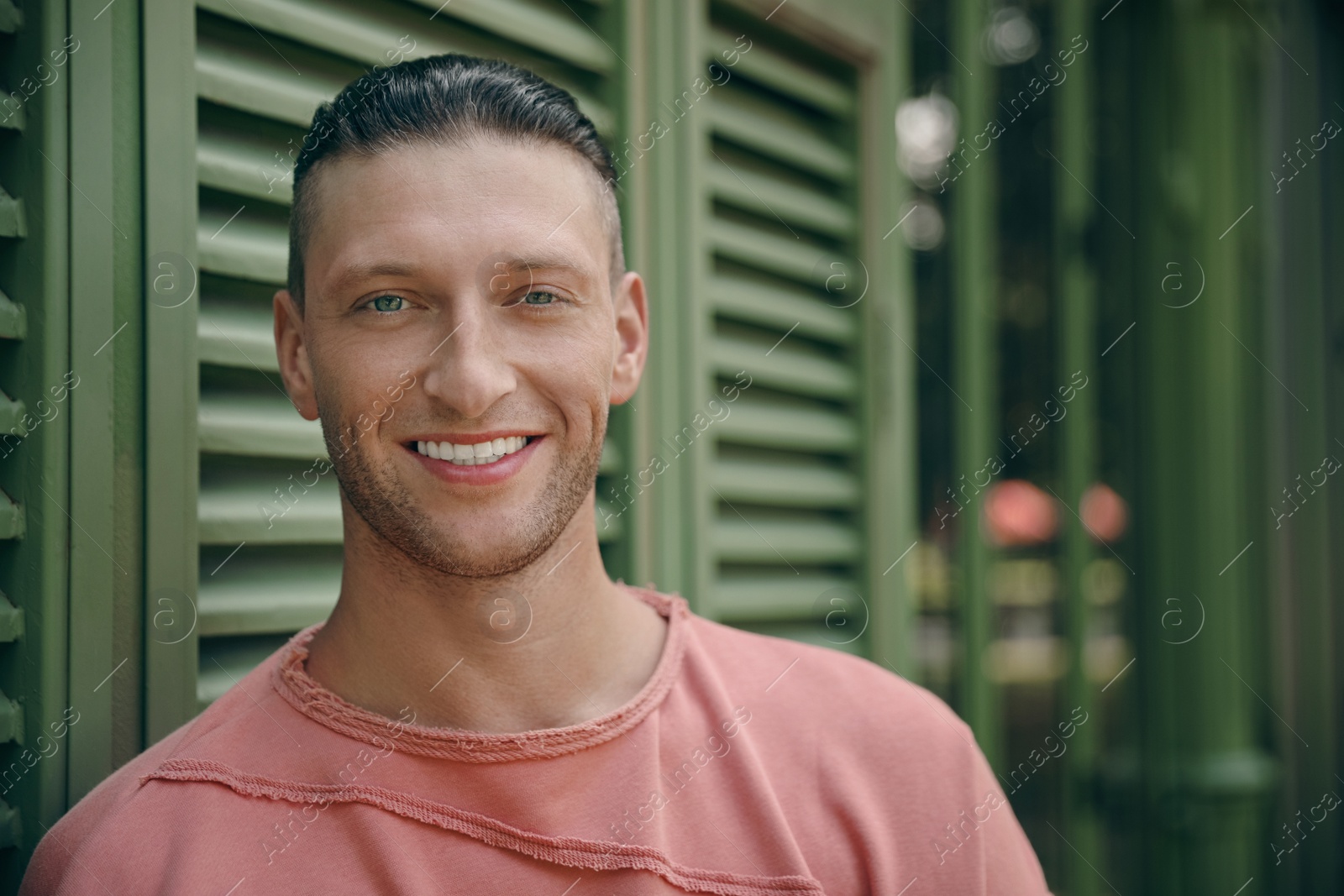 Photo of Handsome young man in stylish outfit near shutters outdoors, space for text