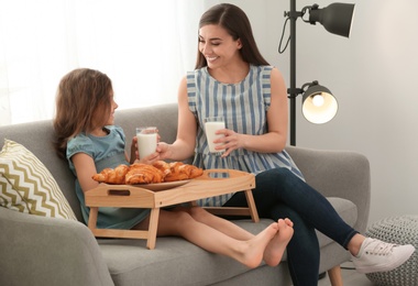 Photo of Mother and daughter having breakfast with milk in living room