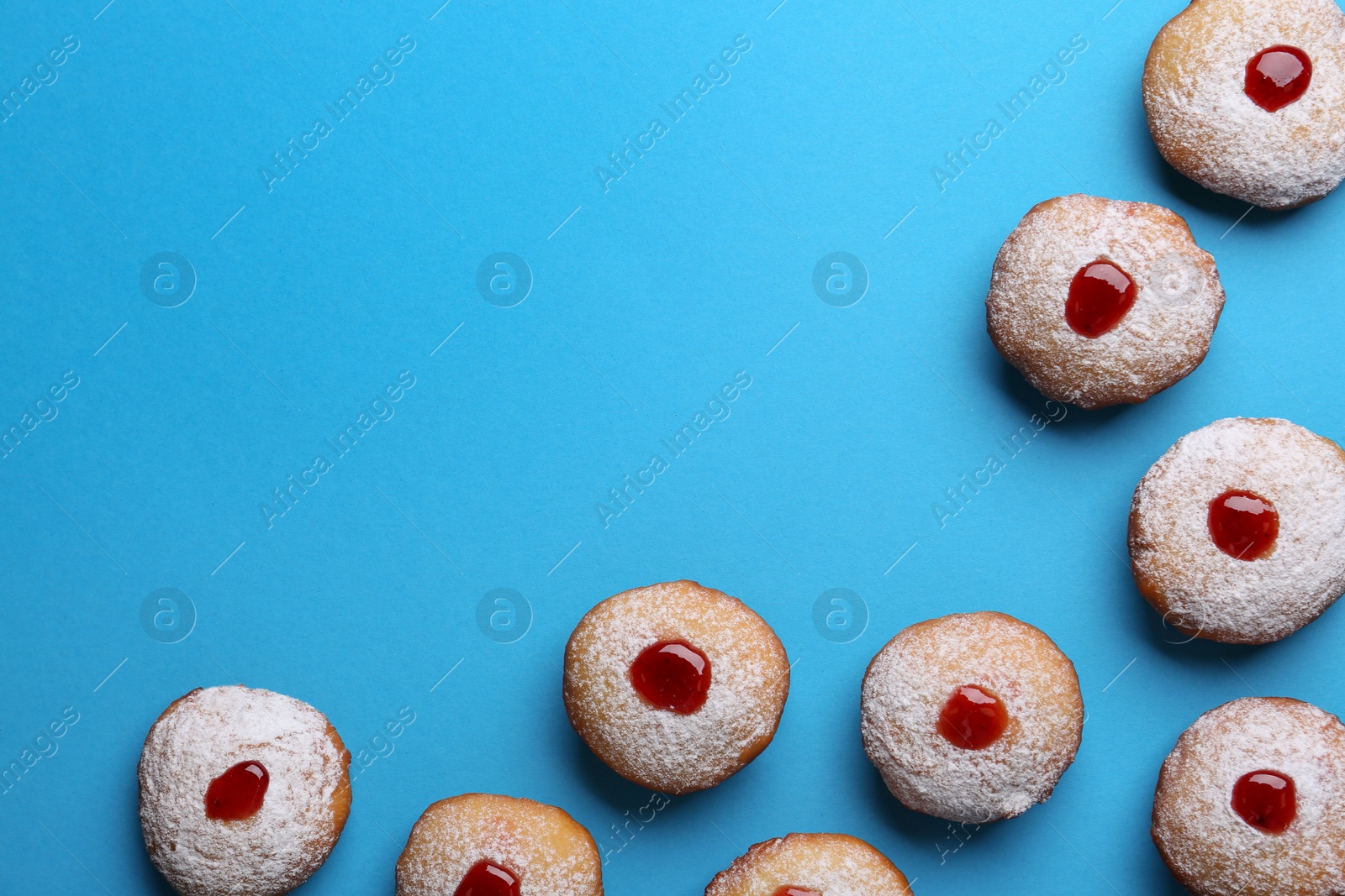 Photo of Hanukkah donuts with jelly and powdered sugar on turquoise background, flat lay. Space for text