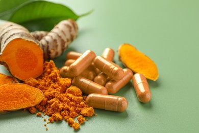 Photo of Aromatic turmeric powder, pills and raw roots on green background, closeup