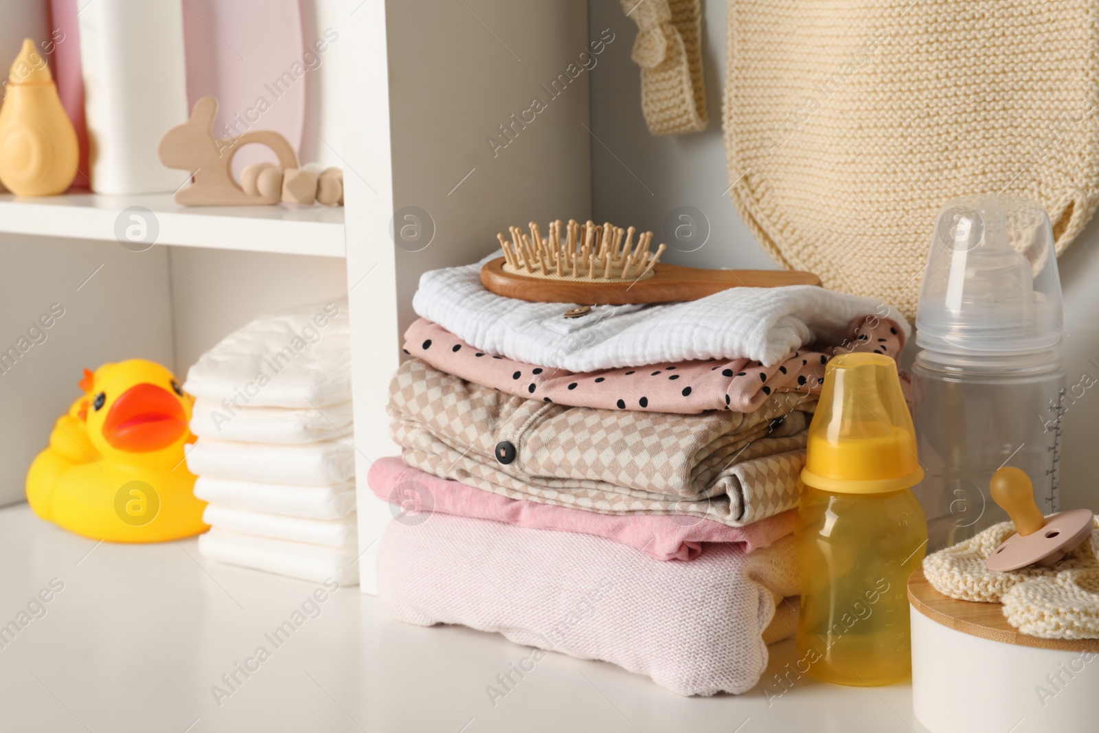 Photo of Baby clothes, toy and accessories on white rack