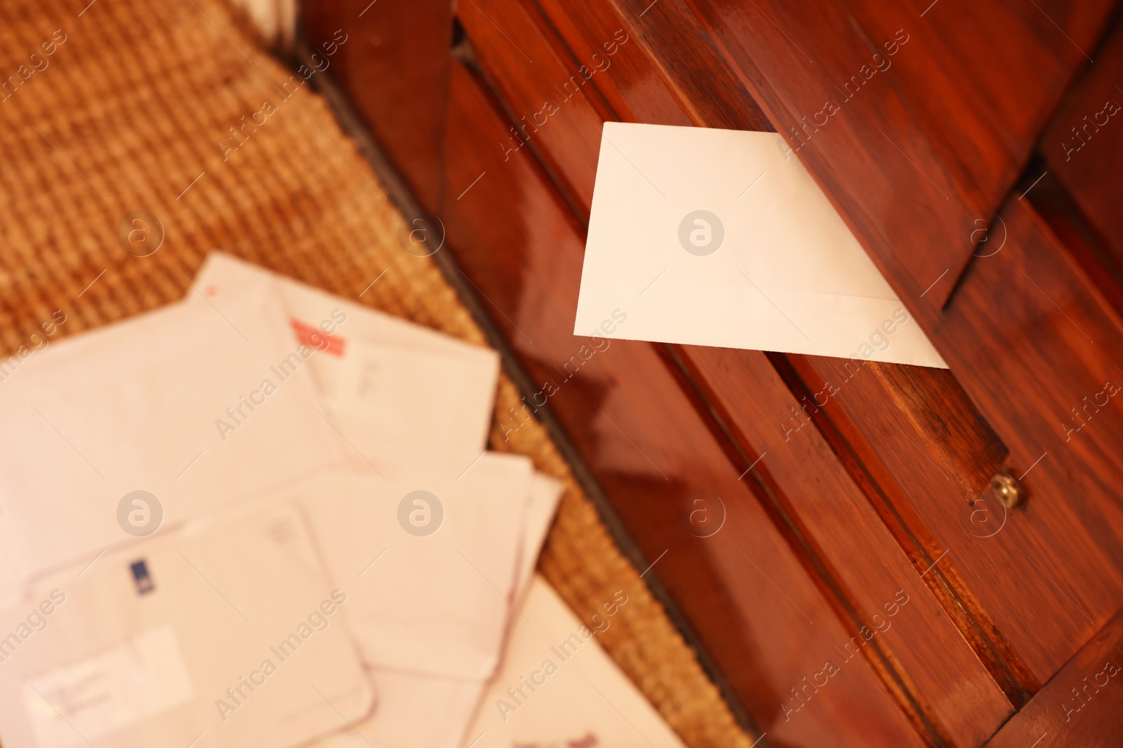 Photo of Mail slot with envelope in wooden door indoors, above view. Space for text