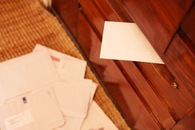 Photo of Mail slot with envelope in wooden door indoors, above view. Space for text