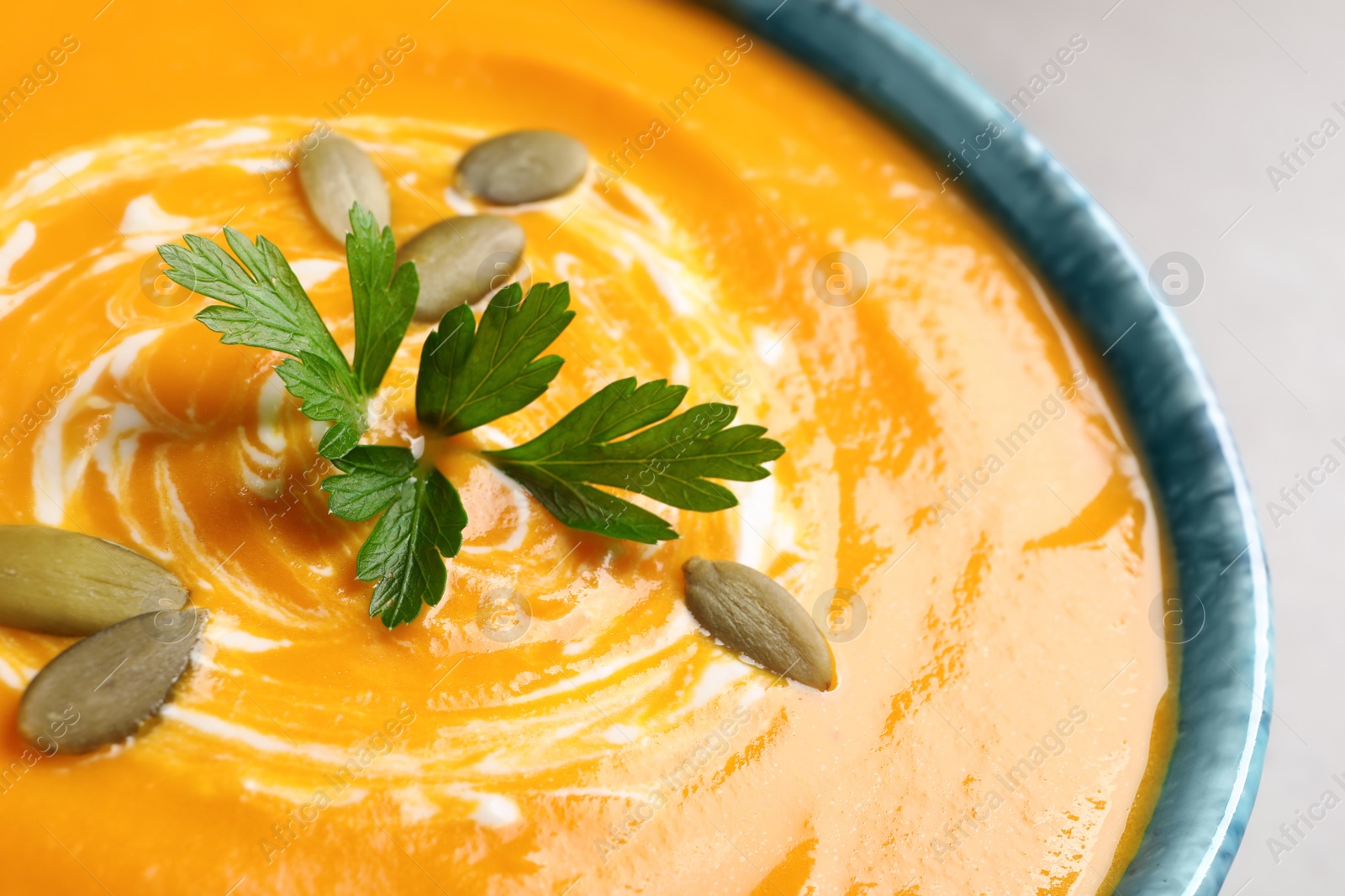 Photo of Tasty pumpkin soup with seeds and parsley in bowl, closeup