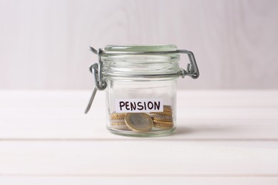 Photo of Glass jar with word Pension and coins on white wooden table, closeup