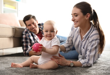 Photo of Happy parents with little baby in living room