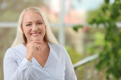 Portrait of beautiful older woman against blurred background with space for text